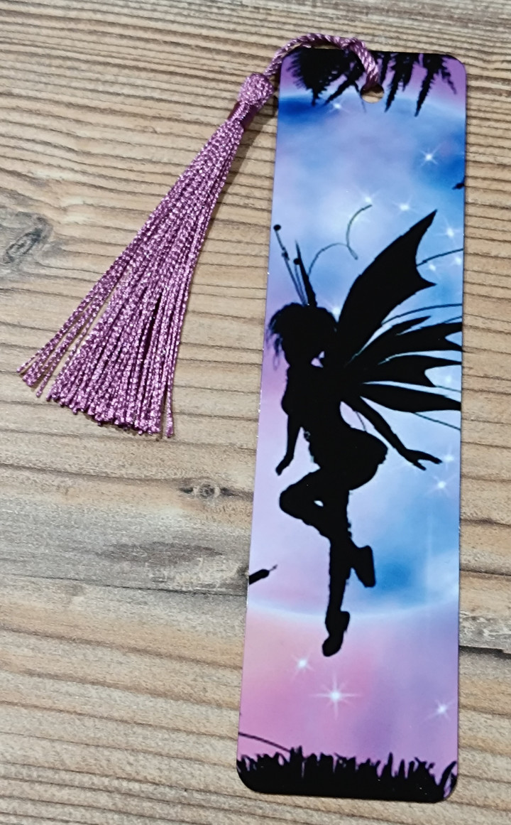 Marque-page avec silhouette noire de fée ailée sur fond étoilé bleu et violet avec pompon assorti