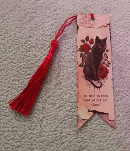 Marque-page style parchemin illustré d'un chat noir aux yeux rouges, de roses et muni d'un pompon rouge