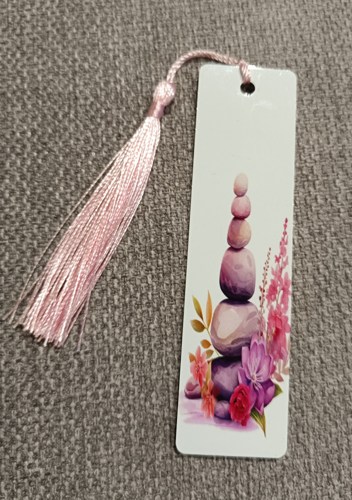 Marque-page blanc orné de galets empilés et de fleurs roses avec pompon rose
