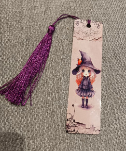 Marque-page illustré d'une petite sorcière au grand chapeau avec un pompon violet