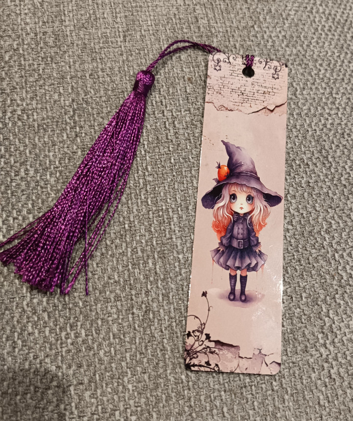 Marque-page illustré d'une petite sorcière au grand chapeau avec un pompon violet