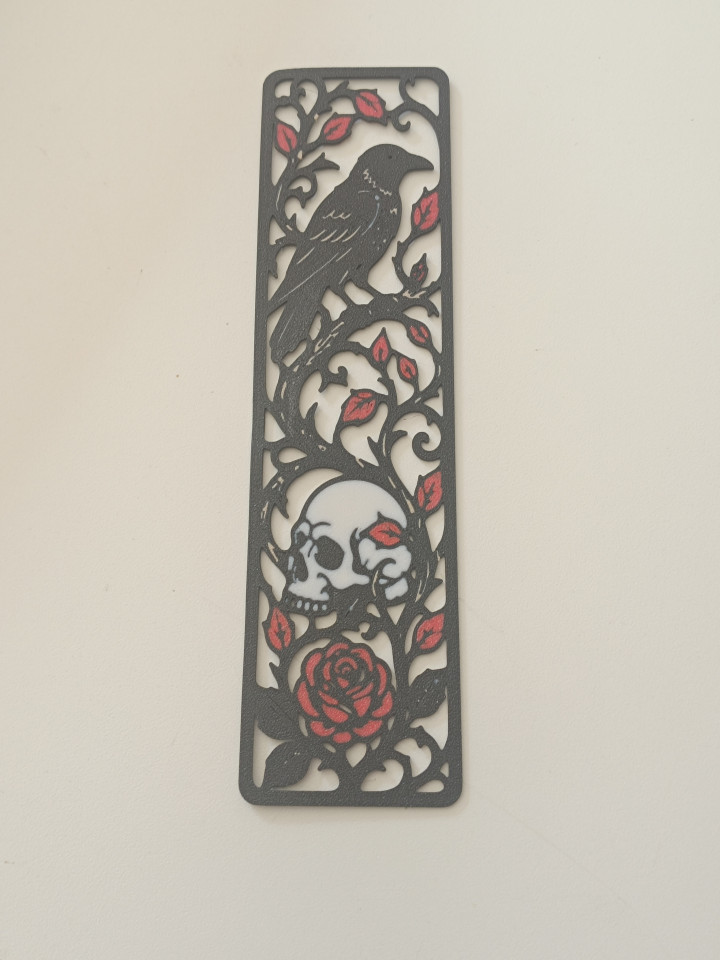 Marque-page noir ajouré orné d'un corbeau sur une branche, d'un crâne et d'une rose rouge