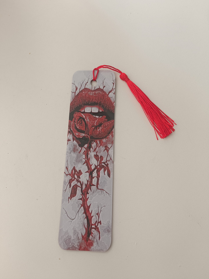Marque-page illustré de lèvres rouges tenant une rose épineuse avec pompon rouge