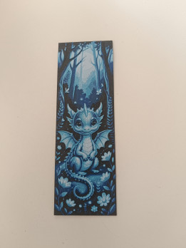 Marque-page en impression 3D illustrant un petit dragon bleu assis dans une forêt aux tons nocturnes