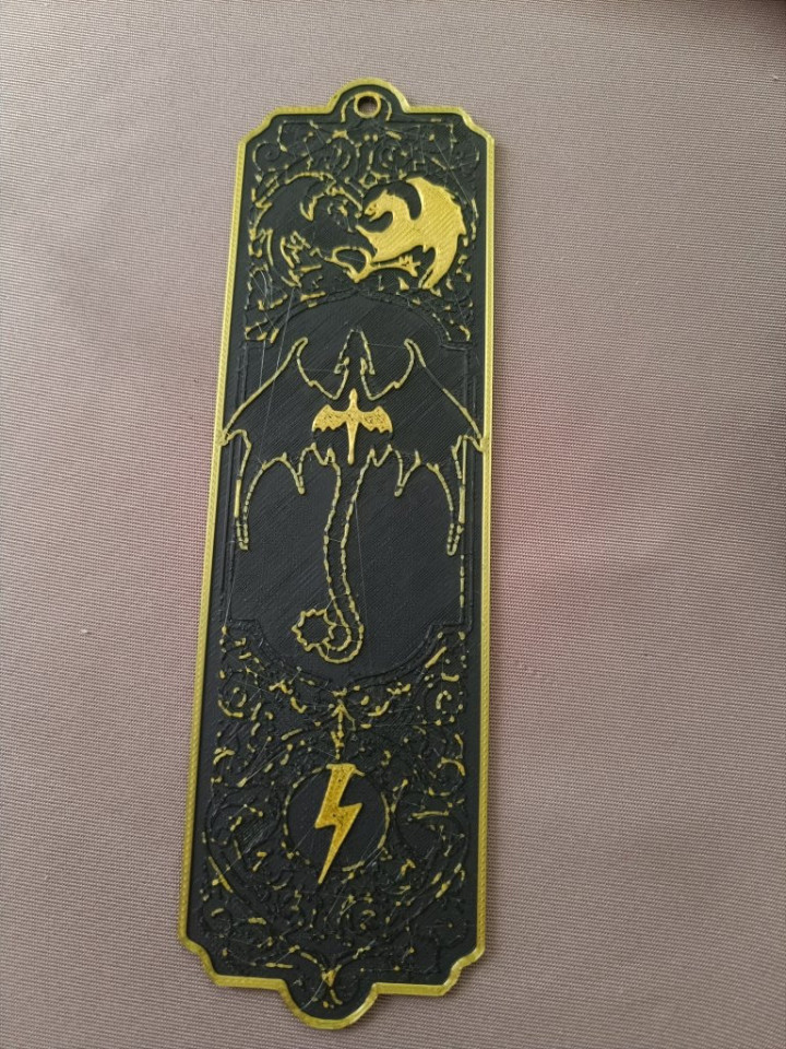 Marque-page noir et doré imprimé en 3D avec motifs de dragons et symbole d'éclair