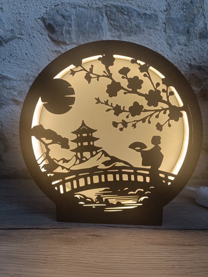 Lampe veilleuse ronde en impression 3D noire représentant une silhouette de paysage asiatique avec pagode et cerisier