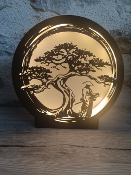 Lampe veilleuse ronde en impression 3D avec silhouette noire de guerrier sous un arbre éclairée par une lumière chaude