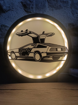Lampe veilleuse circulaire éclairée avec silhouette noire d'une voiture aux portes papillon ouvertes