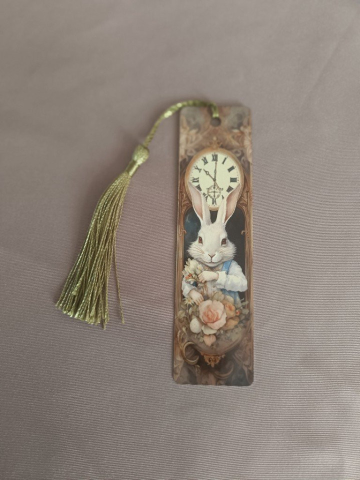Marque-page en métal illustré d'un lapin blanc habillé avec une horloge et un pompon doré