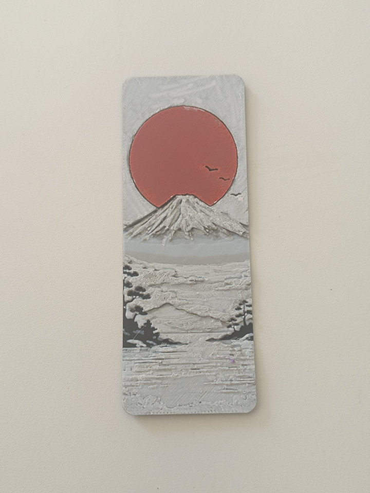 Marque-page en relief représentant une montagne enneigée sous un soleil rouge