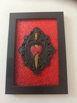 Cadre noir avec cœur rouge transpercé par une dague dorée en relief 3D sur fond scintillant rouge