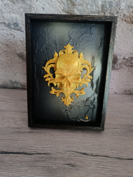 Cadre noir avec impression 3D d'un crâne baroque doré en relief