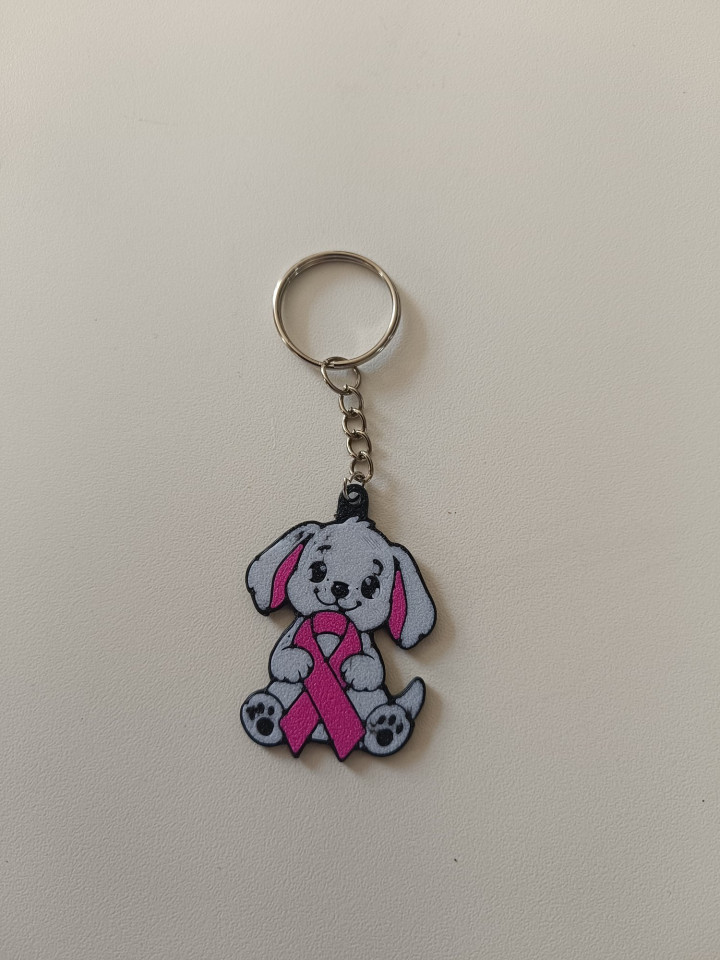 Porte-clés en impression 3D représentant un chiot gris tenant un ruban rose