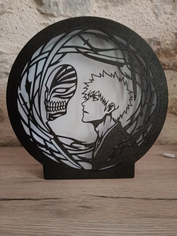 Veilleuse circulaire LED montrant la silhouette d'un guerrier de profil face à un masque squelettique