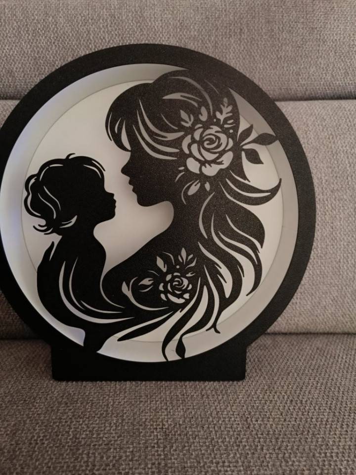 Veilleuse circulaire noire rétroéclairée par LED montrant la silhouette d'une mère et son enfant