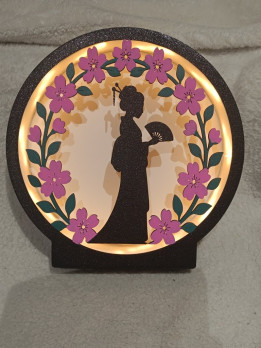Veilleuse ronde lumineuse avec silhouette noire tenant un éventail et couronne de fleurs roses
