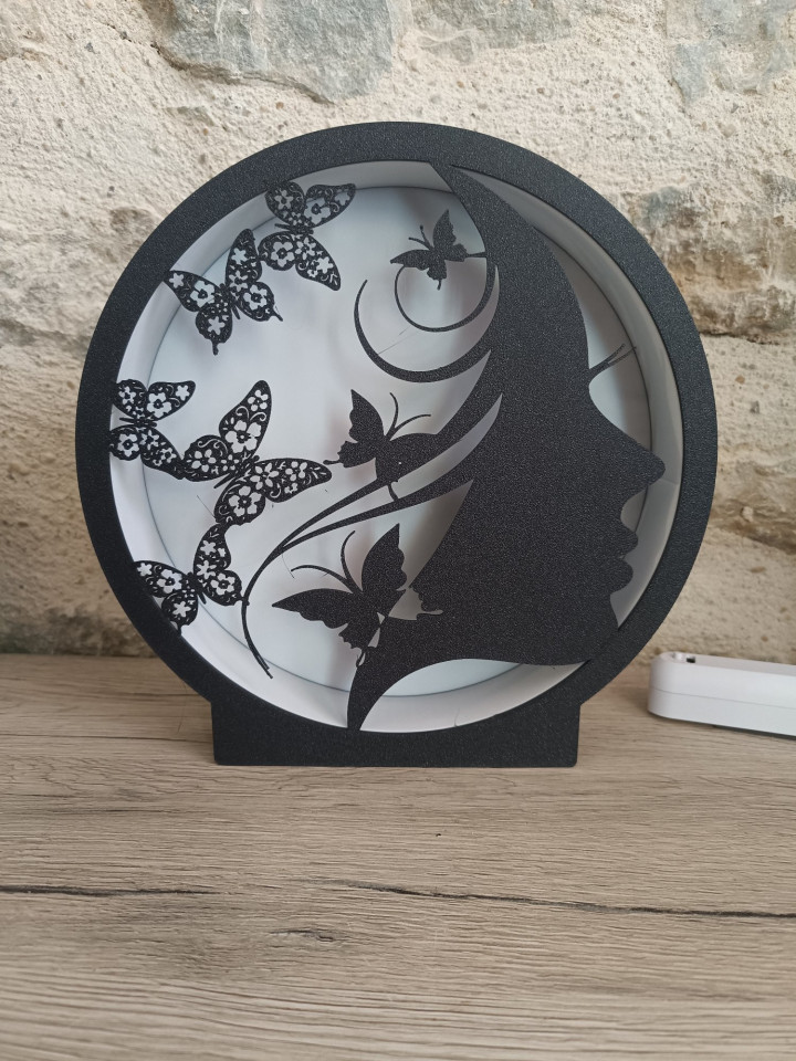 Lampe ronde noire avec silhouette de femme et papillons rétroéclairée par LED
