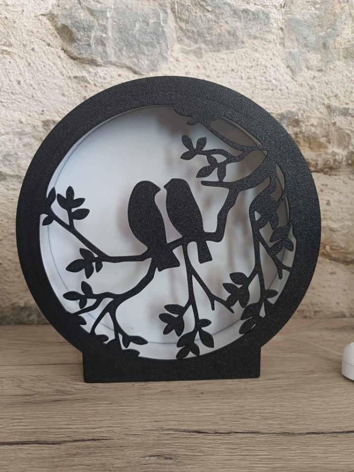 Lampe veilleuse circulaire noire en impression 3D avec silhouette de deux oiseaux sur une branche rétroéclairée