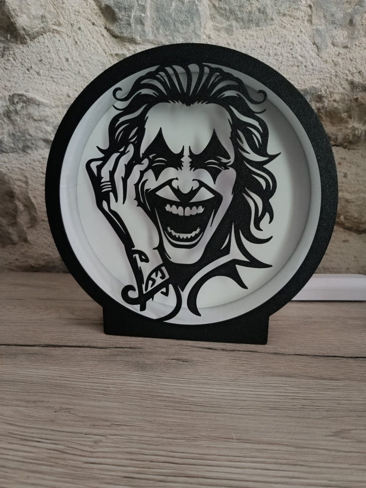 Lampe circulaire en impression 3D avec silhouette noire d'un clown au rire démoniaque sur fond blanc