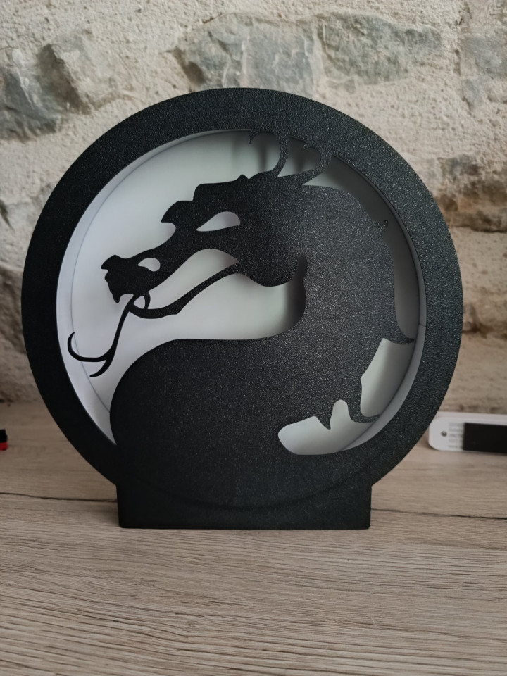 Lampe circulaire noire représentant une silhouette de dragon rétroéclairée par une douce lumière LED
