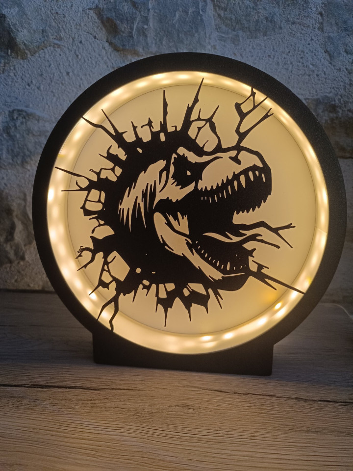 Lampe ronde noire en impression 3D avec éclairage LED et silhouette de dinosaure surgissant d'une brèche