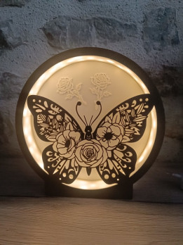 Veilleuse circulaire noire allumée avec silhouette de papillon ajouré orné de roses