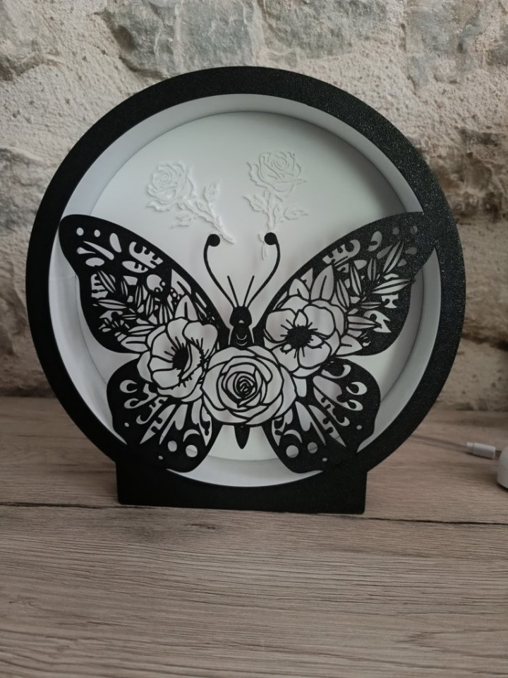 Veilleuse circulaire noire allumée avec silhouette de papillon ajouré orné de roses