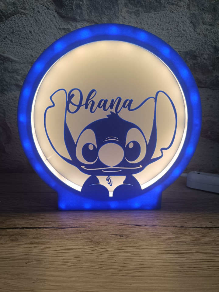 Veilleuse circulaire lumineuse bleue avec silhouette de créature aux grandes oreilles et inscription Ohana
