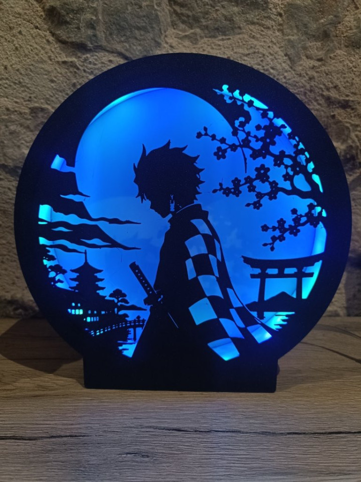 Veilleuse ronde en impression 3D éclairée en bleu avec silhouette d'épéiste au sabre sous la lune