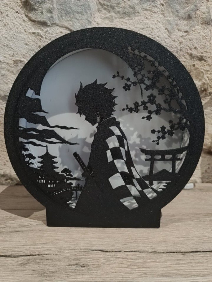 Veilleuse ronde en impression 3D éclairée en bleu avec silhouette d'épéiste au sabre sous la lune