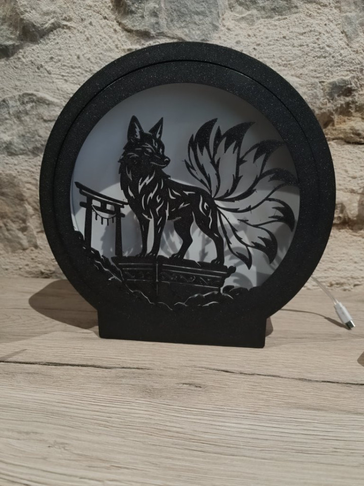 Veilleuse circulaire noire allumée avec silhouette de renard à neuf queues et portique traditionnel