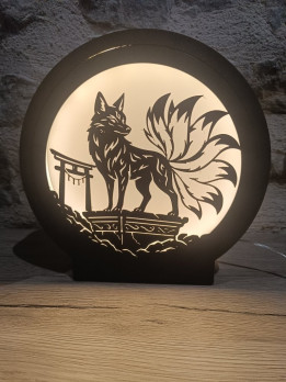 Veilleuse circulaire noire allumée avec silhouette de renard à neuf queues et portique traditionnel