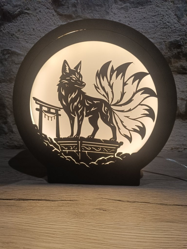 Veilleuse circulaire noire allumée avec silhouette de renard à neuf queues et portique traditionnel
