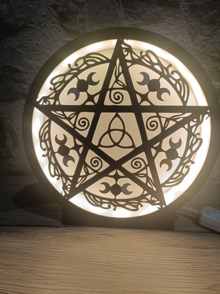 Lampe circulaire noire allumée avec silhouette de pentagramme, triquetra et croissants de lune